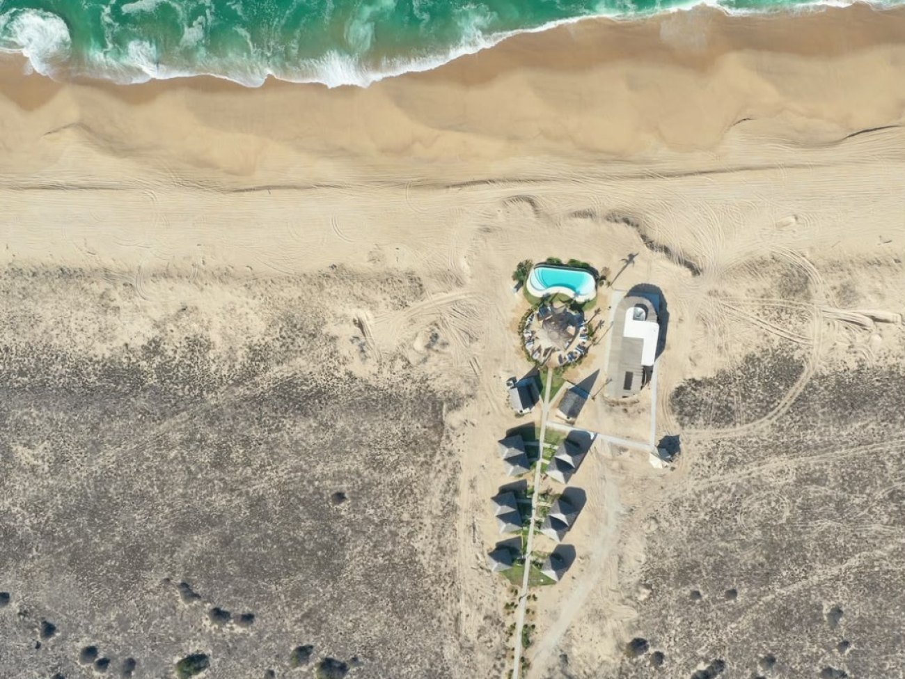 Vista aérea del hotel de Mayto: suites con techo de palapa y alberca a pie de la playa de Costalegre